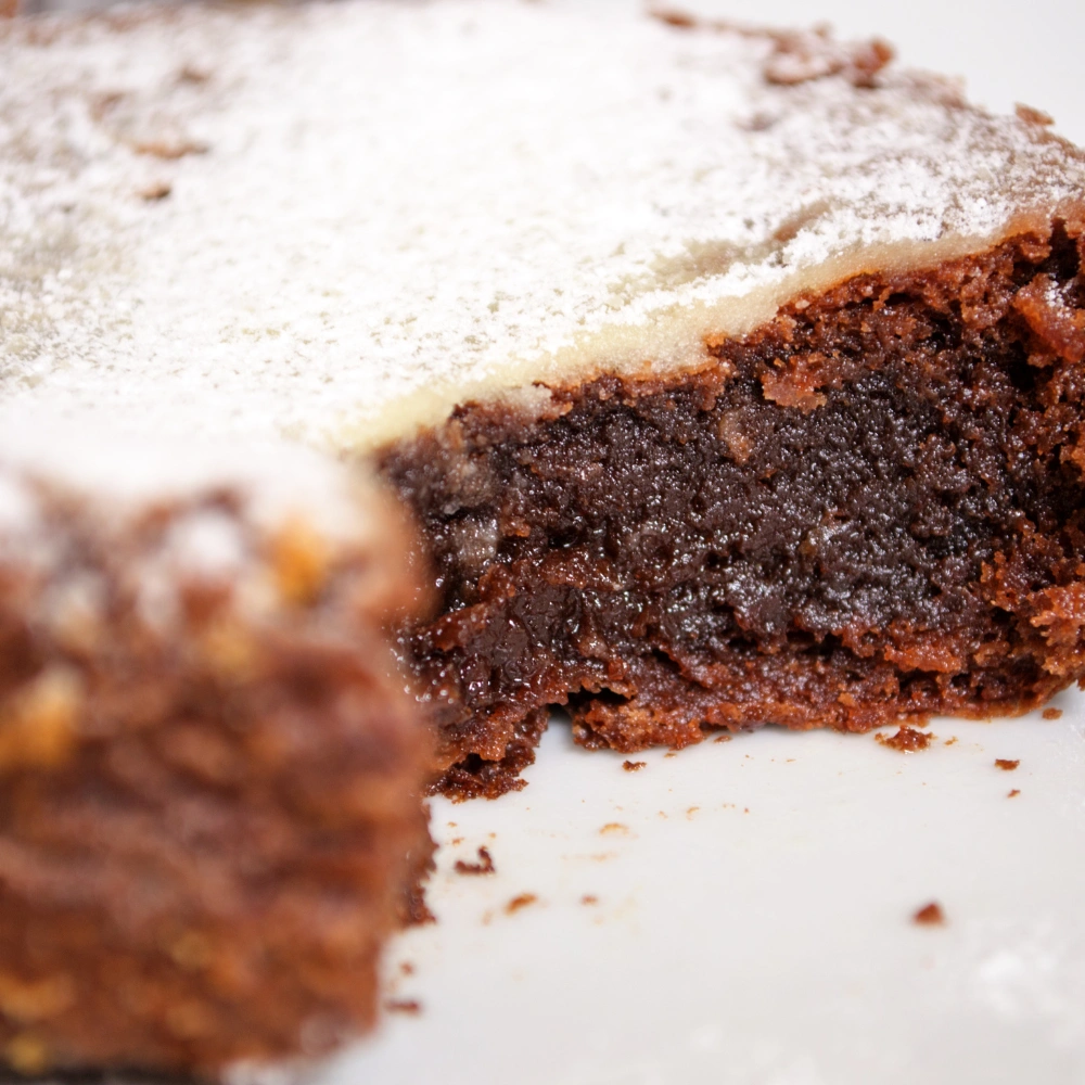 Close-up of a rich fudgy chocolate brownie dusted with powdered sugar, freshly baked at a Korean bakery in Hanoi
