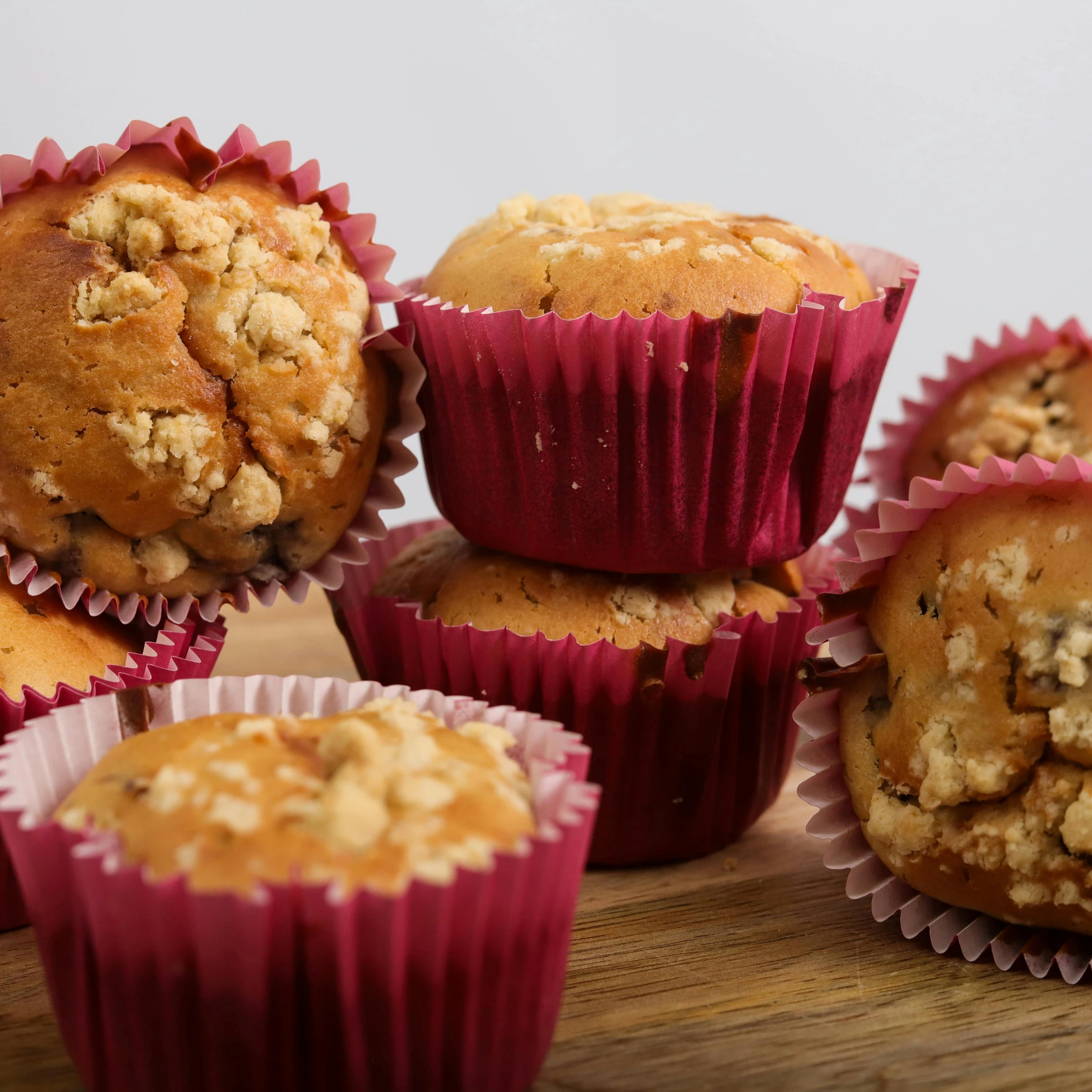 Assorted fresh muffins in pink cupcake liners stacked on a wooden board at Vonado Bakery in Hanoi