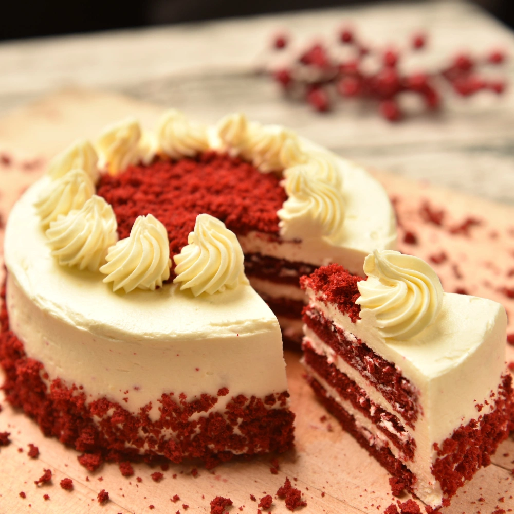 Sliced red velvet layer cake with cream cheese frosting and piped rosettes, served at a Korean bakery in Hanoi